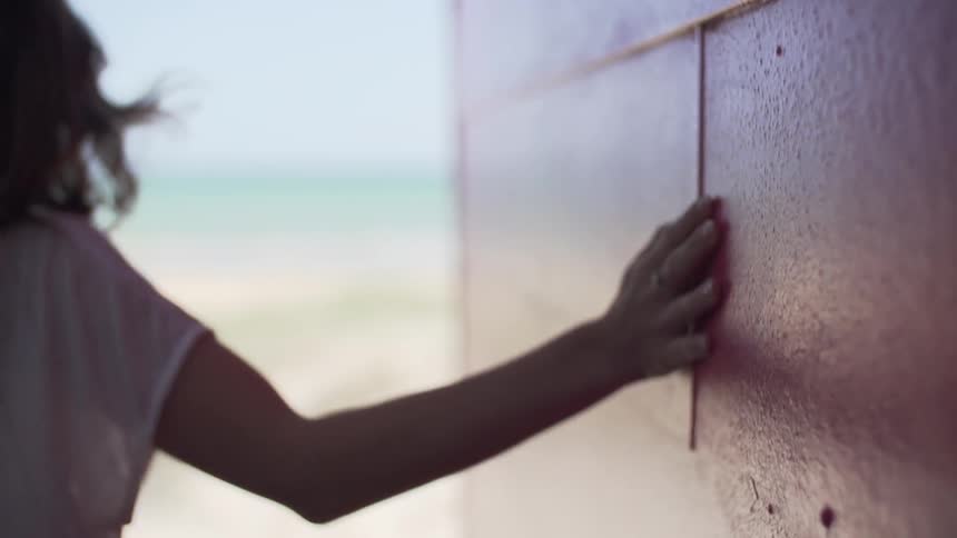 Woman sliding her hand across a wall as she walks