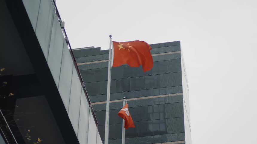 A chinese flag flies atop a building on a cloudy day