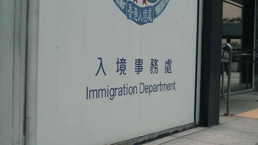 A white sign displays the words immigration department in both english and chinese characters on the exterior wall of a building in hong kong