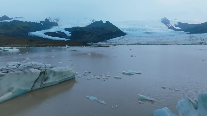Ice blocks floating in a glacial lake surrounded by snowcovered mountains