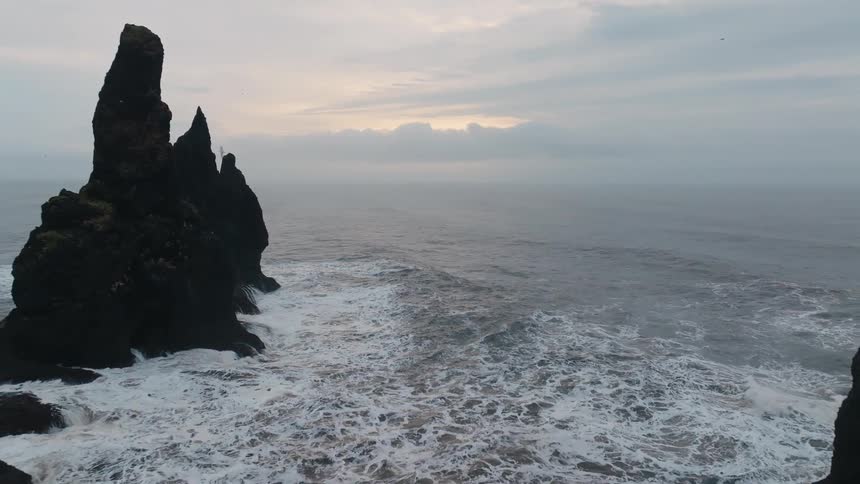 Birds fly around the rocks in the ocean
