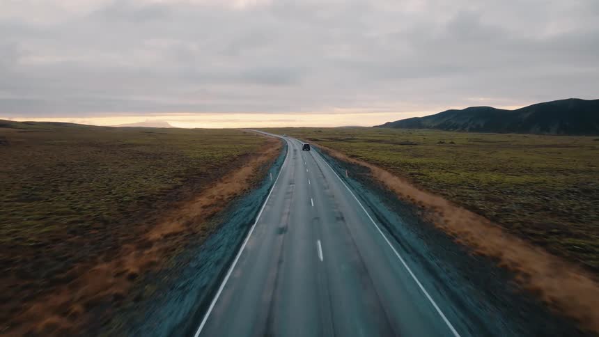 A car drives down a long open road