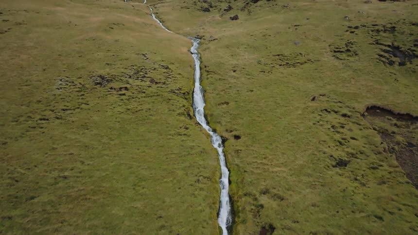 Small waterfall winding through a mosscovered field