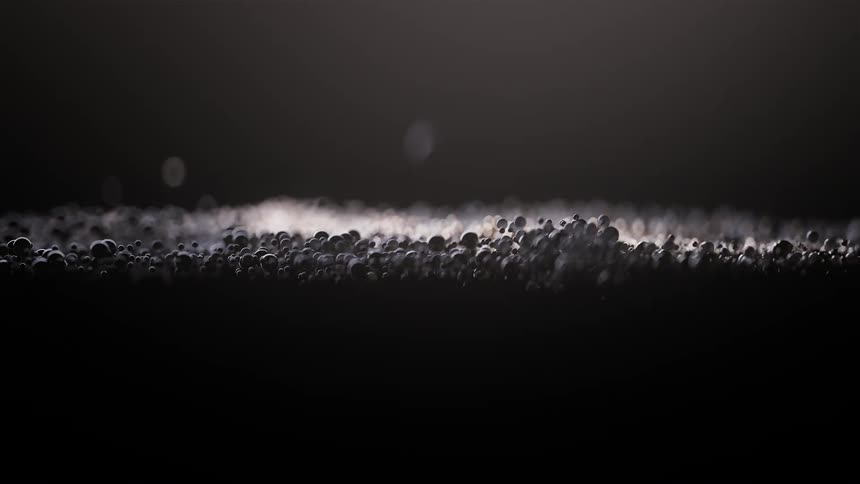 Shimmering droplets reflecting light on a dark surface