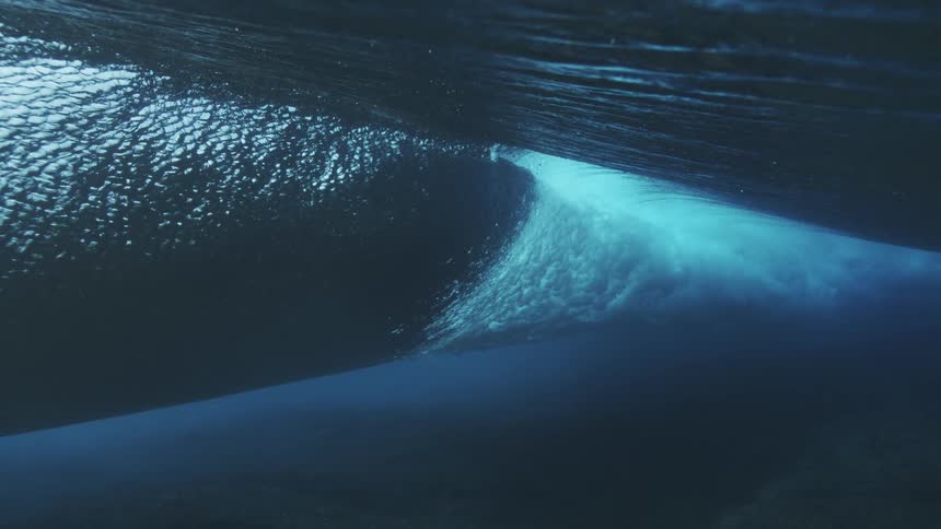 Wave seen from underwater reveals deep blue tones and fluid motion