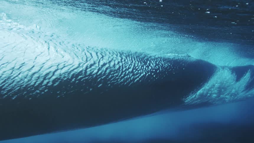 The large wave crashes and dips underwater