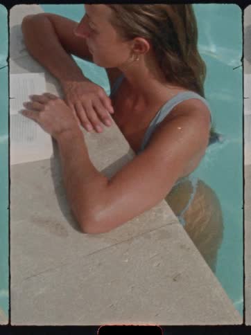 Woman reading while leaning on the edge of a pool