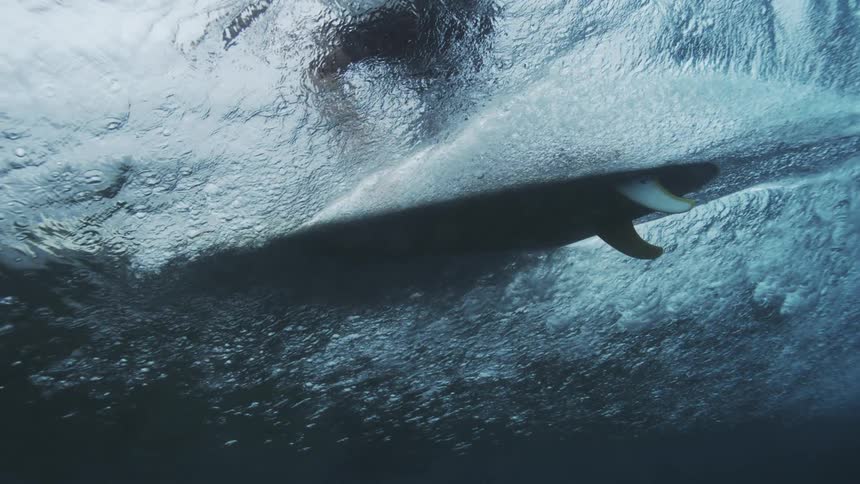 Surfer passing overhead is obscured by the translucent water of the wave being ridden