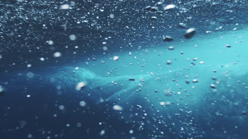 Crystalclear wave captured underwater reveals textures and translucent blue tones