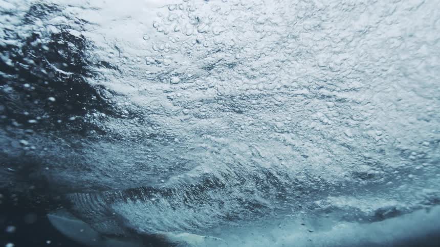 Translucent water of a wave obscures a surfer before the individual falls off their surfboard