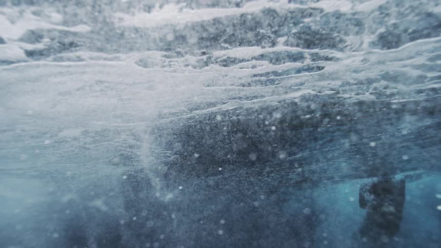 Person wearing a wetsuit swims through foaming ocean water