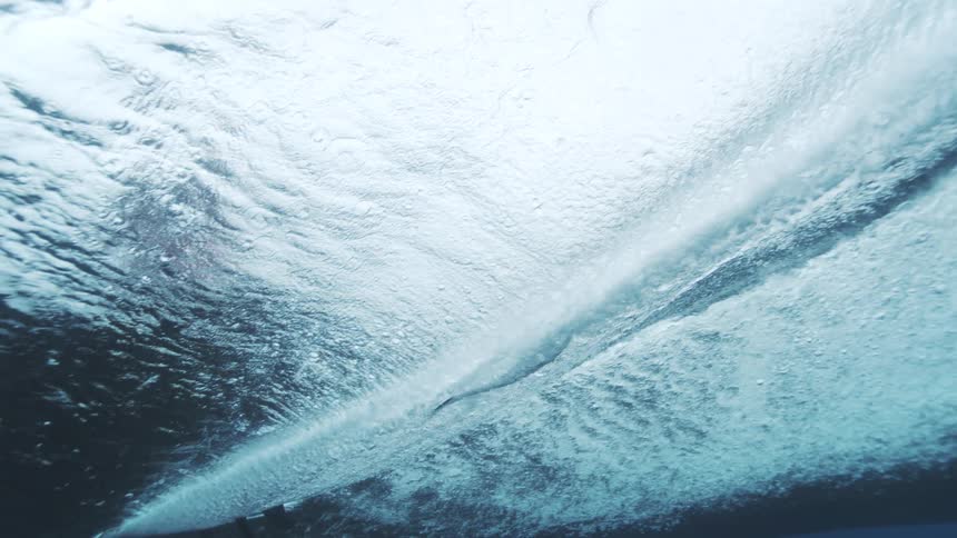 The surfboard moves along the water above