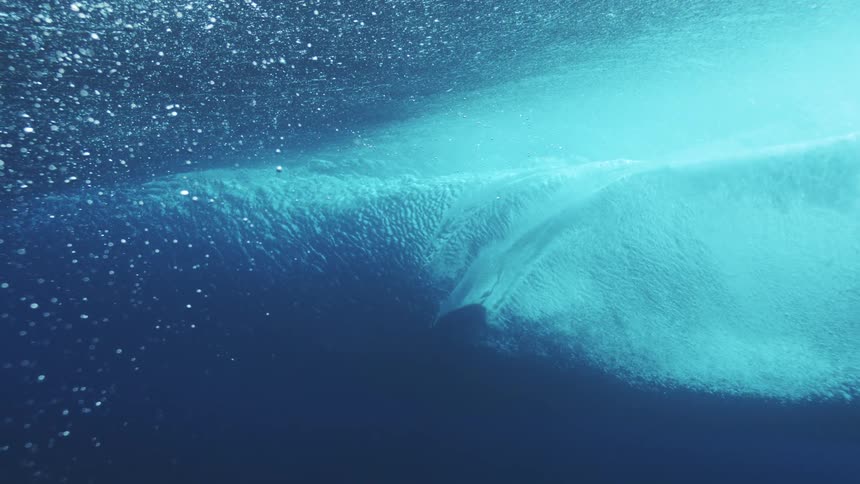 The surfboard cuts through the water above
