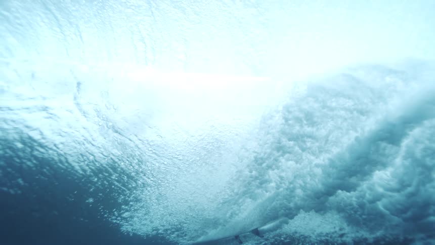 Bubbles fill the water as a surfer passes overhead on a rolling wave