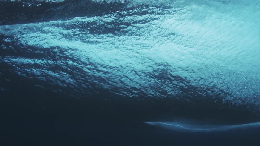 Underwater view of a surfer riding the barrel of a wave