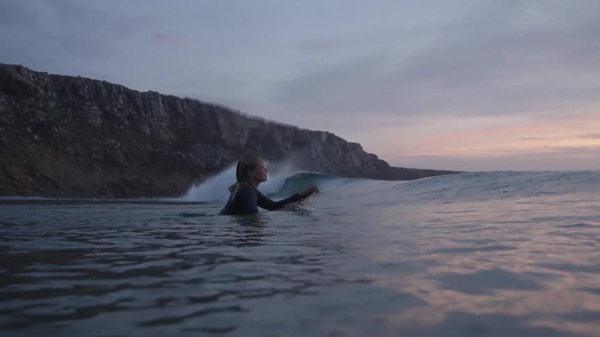 The woman is surfing at sunrise