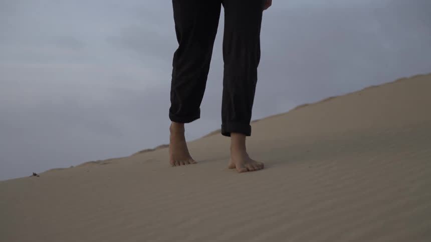 The woman walks along the sand