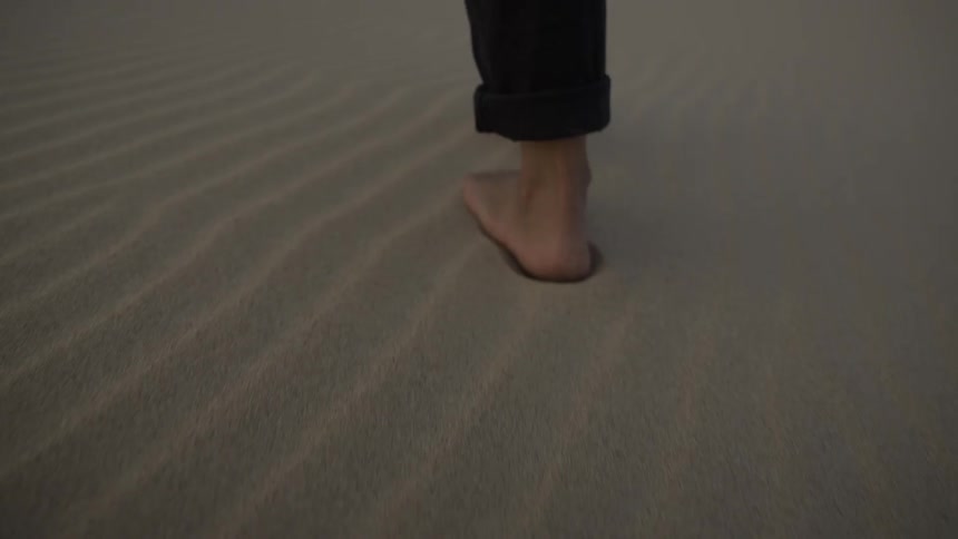 Person walks barefoot on the beach after sunset