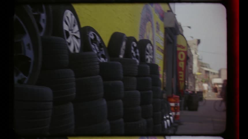 Stacked tires line a commercial garage while a male cyclist stands near the garage entrance