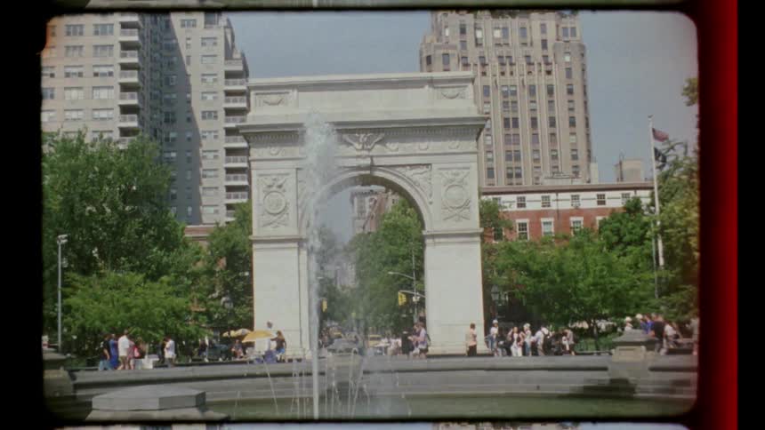 A city park and a fountain in the foreground with trees people and tall buildings lining the perimeter of the public square