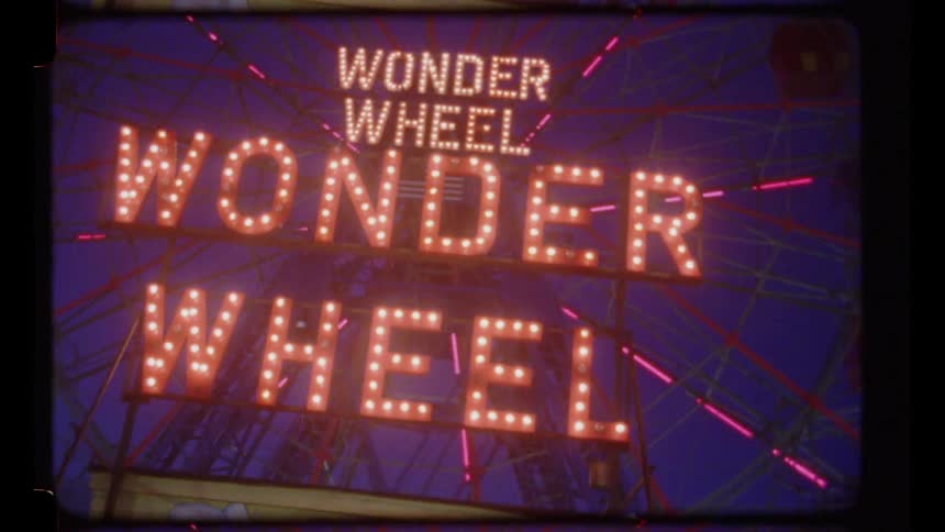 An amusement park with a sign on a wheel ride that reads wonder wheel at night