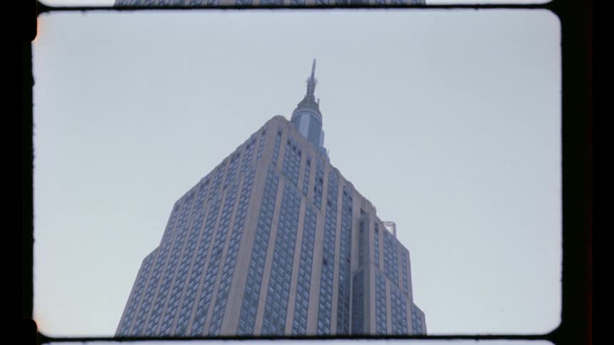 A tall empire state building rises against the sky