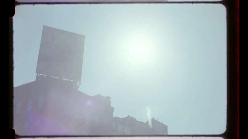 A city street view with a billboard mounted atop a highrise building at sunset