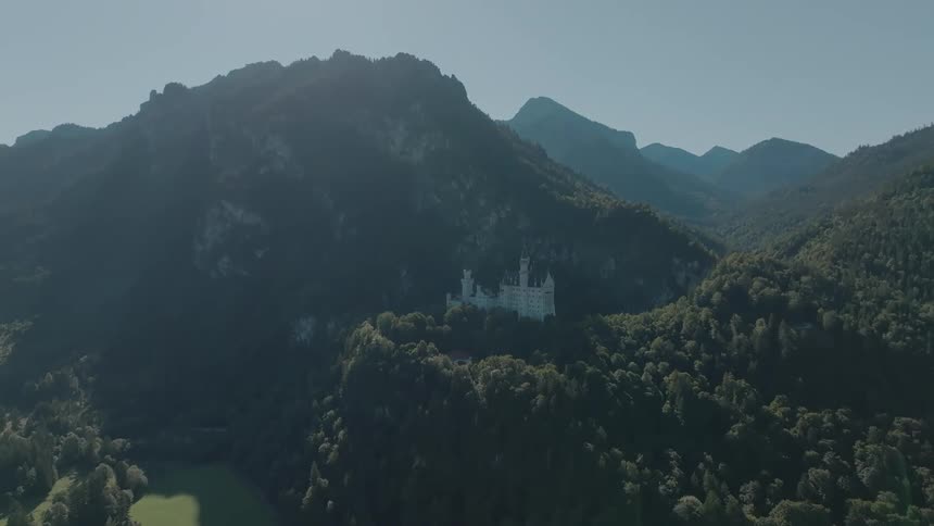 Aerial view of a mountain range with a castle nestled in the forest