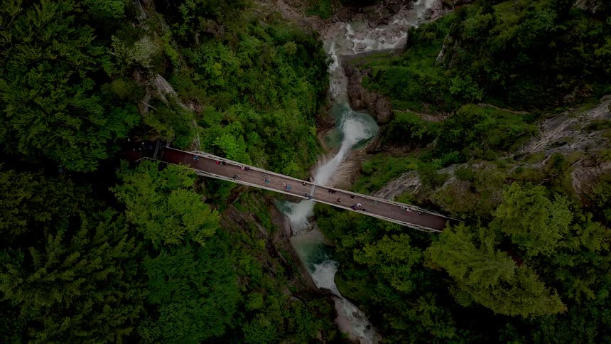 Aerial view of a bridge over a forested gorge with a waterfall