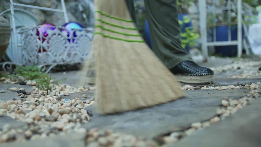 Person sweeps the gravel in order to fill the space between flagstones during the daytime