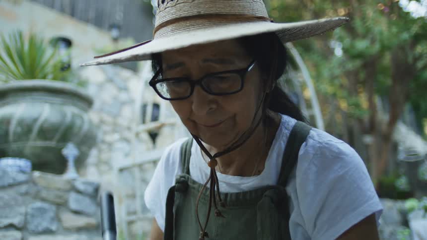Woman in a straw hat works in a garden