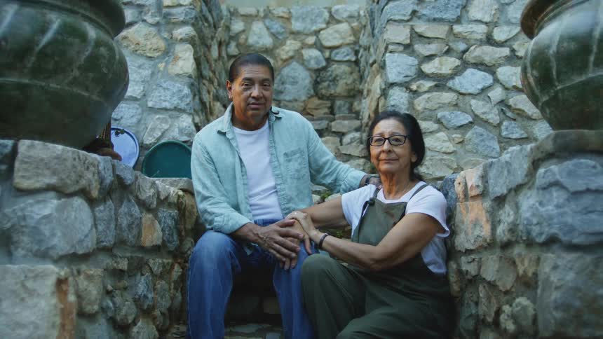 The man and woman sit together on the stone steps