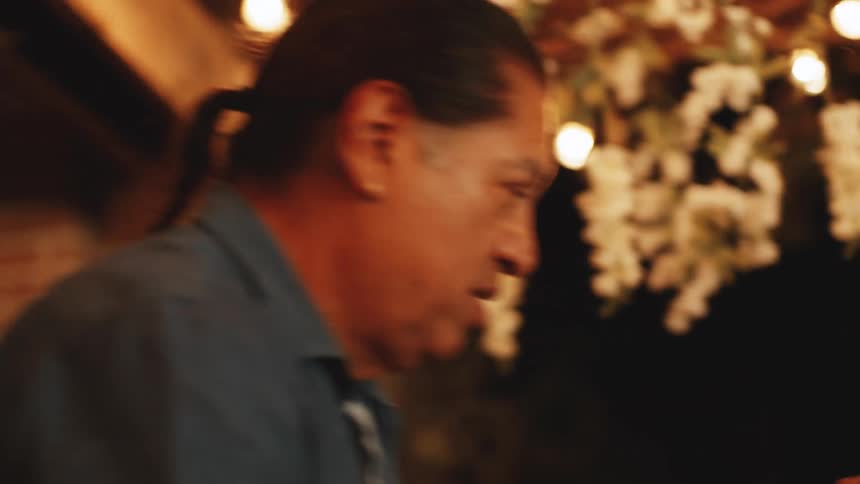 Woman claps while watching two people dance together on the porch at night