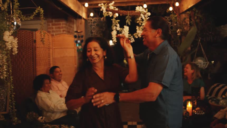 The man spins the woman as they dance in the yard