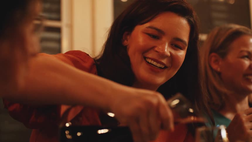 Hand pouring red wine into a glass during dinner