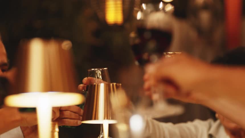 A group of people make a toast with wine glasses in a dimly lit restaurant