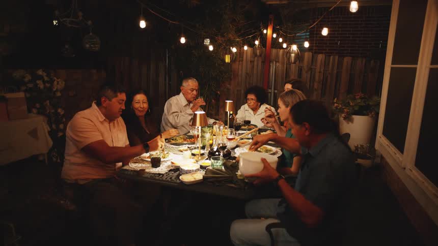 Family gathered for an outdoor dinner under hanging lights at night