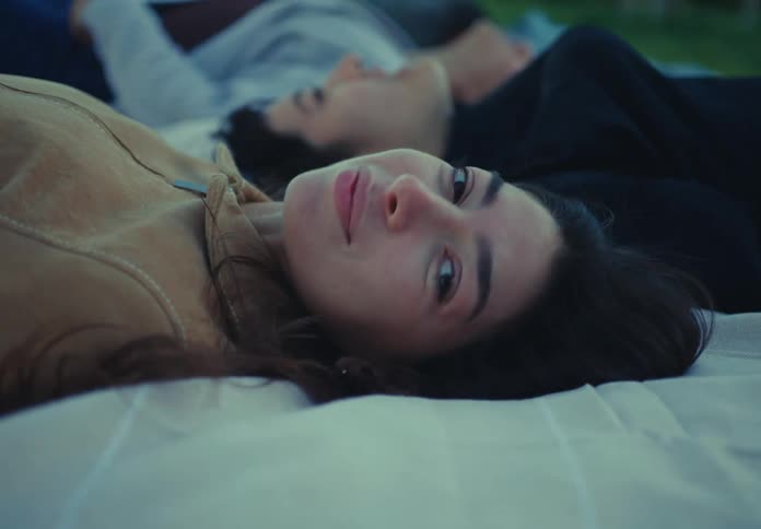 People lying on blankets gaze at the sky during dusk