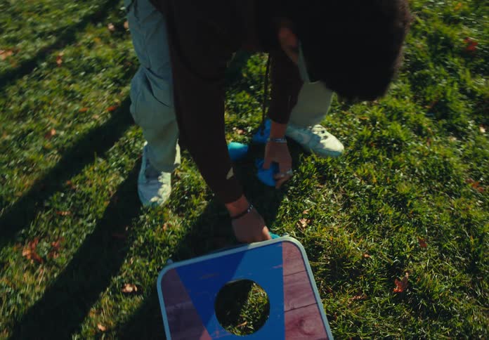 Person sets up the toss game board on the grass