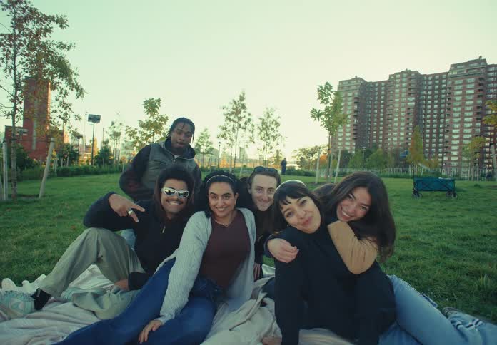 A group of friends posing for photos while at an outdoor picnic in a city park during daytime