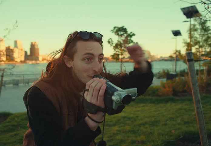 The man is recording with a camcorder by the water