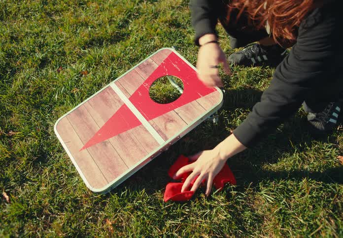 The man drops bean bags and a target on the grass