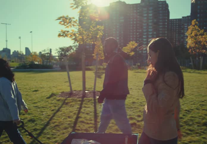 Friends walk through a park pulling a wagon under the afternoon sun