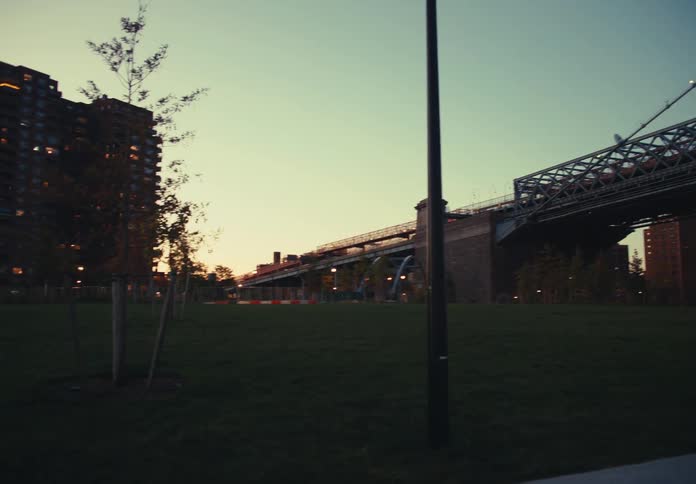 Residential buildings lit up at nightfall with treelined park in the foreground