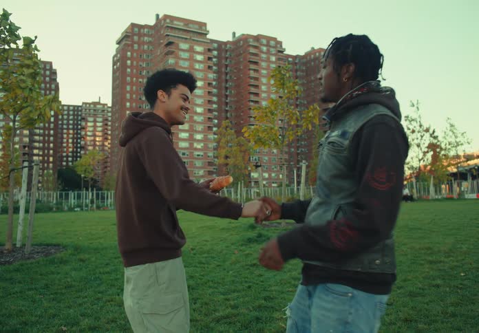 Some friends play a hacky sack target game while having a picnic in a park located near an apartment complex on an autumn day