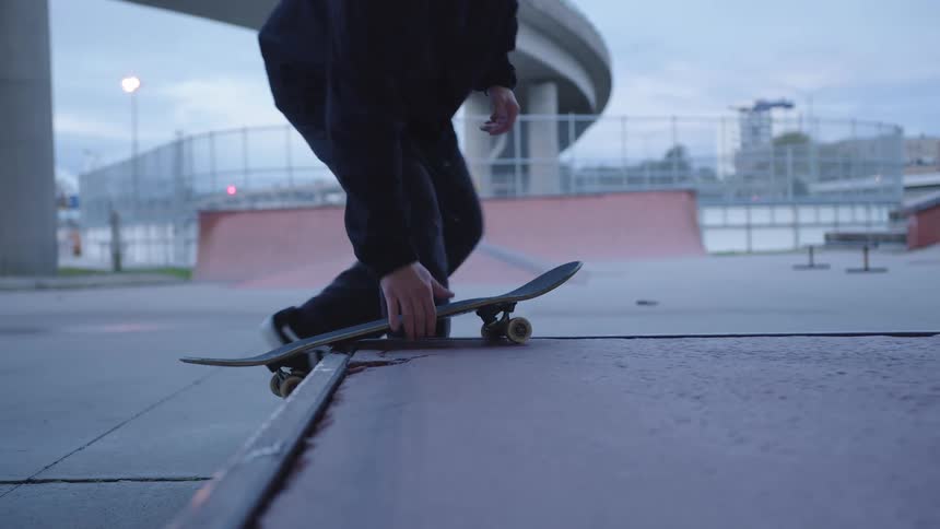 Person gets ready to skateboard at a skate park during dusk