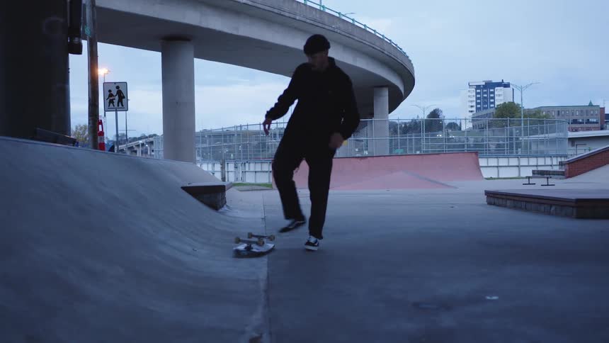 Male skateboarder performs a jump trick before picking up his skateboard and walking away