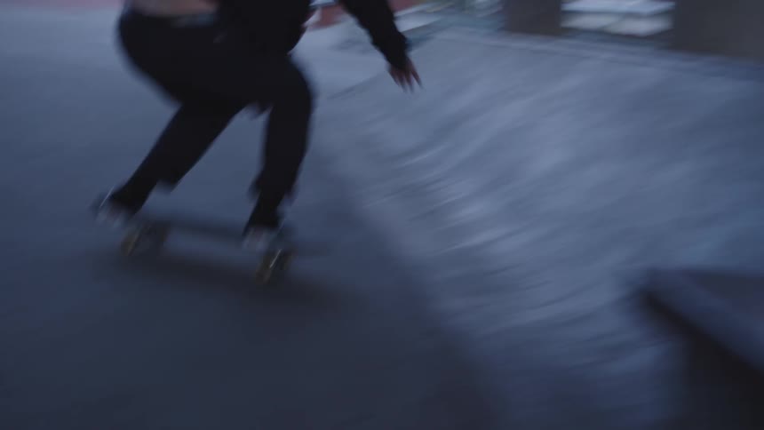 A man rides his skateboard and slides across a concrete wall