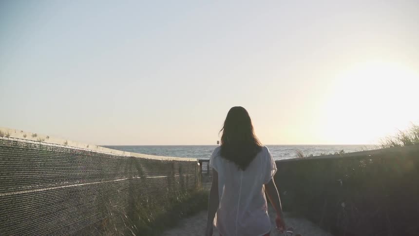 Woman walking down a path towards the water