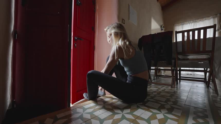 Blonde woman putting on shoes and standing up